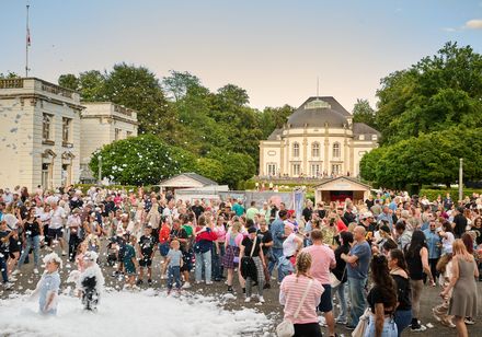 Große Schaumparty und laute 90er Musik im Rahmen der Parklichter am Samstag zum Veranstaltungsmotto "Feel the 90s". Jubelnde und tanzende Menschenmenge. 