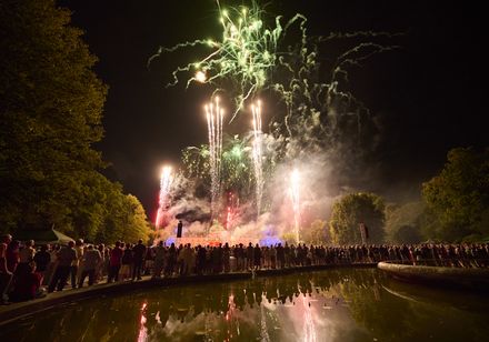 Musiksynchrones Höhenfeuerwerk über dem Kurhaus bei den Parklichtern 2022, Publikum blickt in den Himmel, Spiegelung im Brunnen im Kurpark.