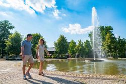 Paar spaziert am Jordan-Sprudel im Kurpark Bad Oeynhausen bei sommerlichem Wetter