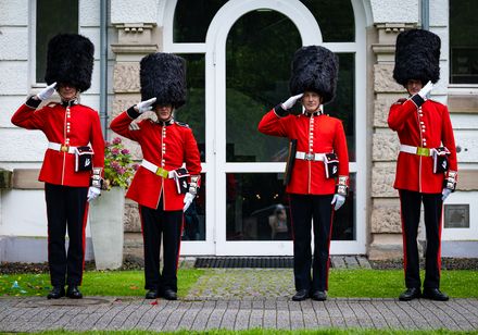 Britische Gardisten in roten Uniformen mit Bärenfellmützen salutieren vor der Tourist Information im Kurpark bei den Parklichtern 2024 unter dem Motto „Very British“.