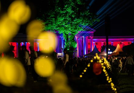Parklichter 2024 im Kurpark: Wandelhalle mit ionischen und dorischen Säulen in Rot und Blau illuminiert – Lampigongs sorgen für britisches Flair
