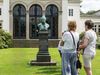 Gruppe bei einer historischen Stadtführung vor der Carl von Oeynhausen Büste am Badehaus I im Kurpark Bad Oeynhausen