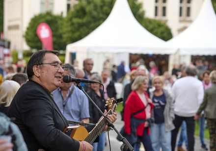 Griechischer Musiker mit Gitarre und Mikrofon singt live bei den Parklichtern 2025 zur Griechischen Nacht im Kurpark vor Publikum.
